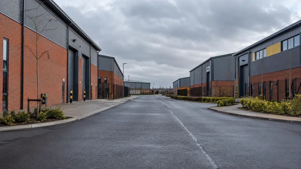 Commercial access road between traditional brick industrial buildings and modern warehouse units